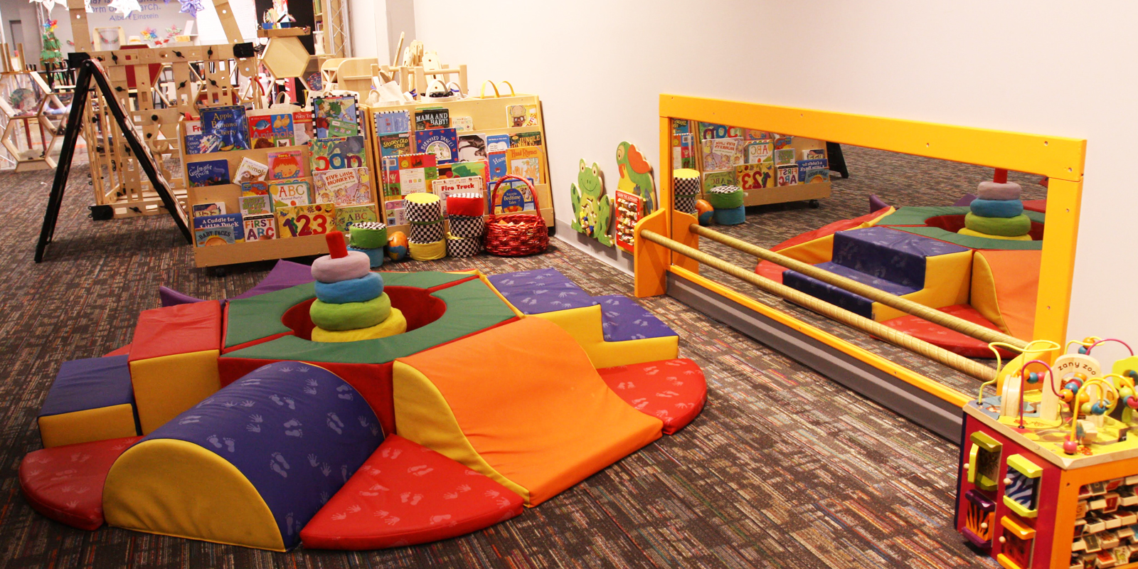 Play area with patterned carpet and bright colorful plush toys and books