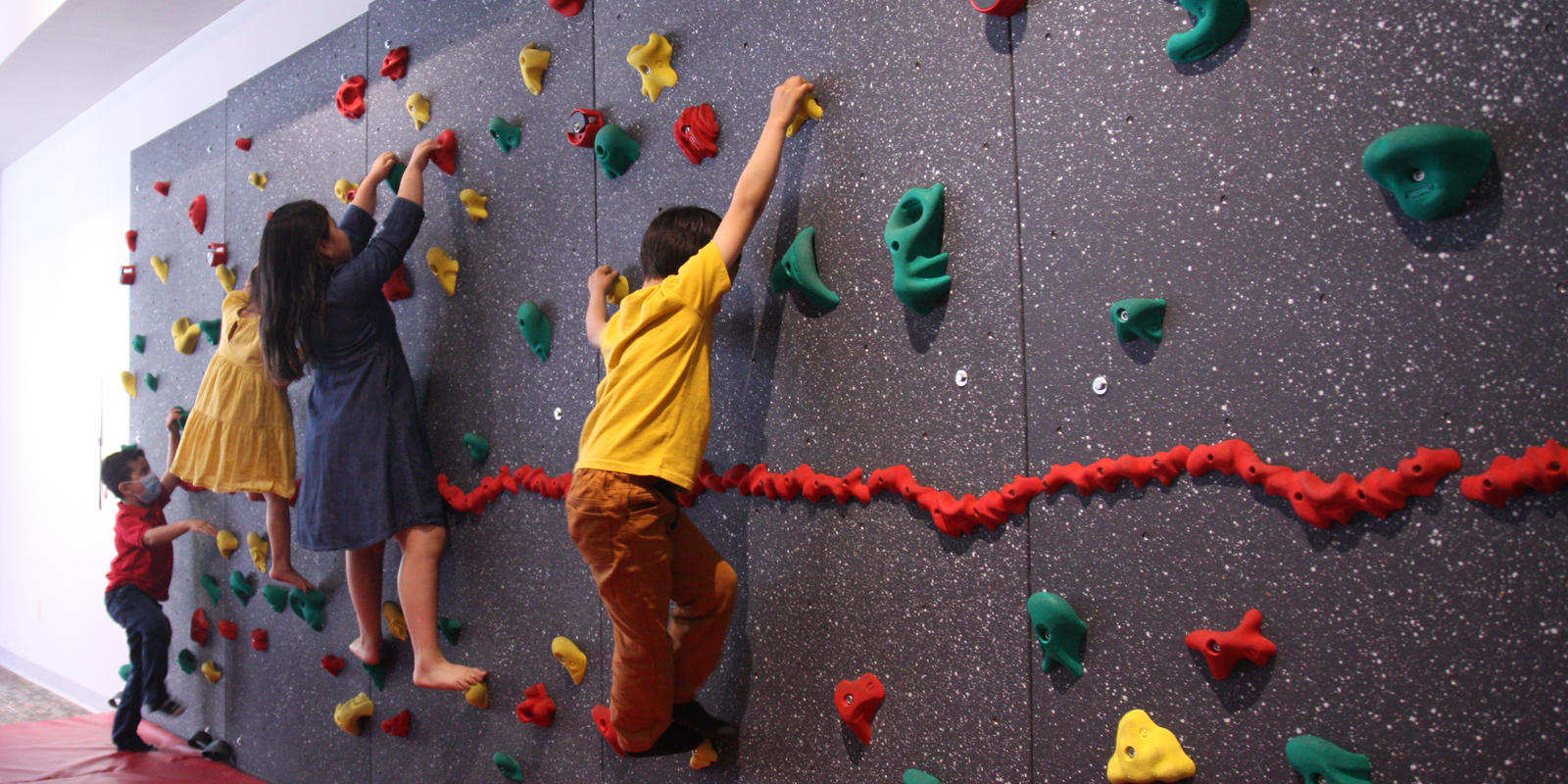 Young children climbing a play rock wall
