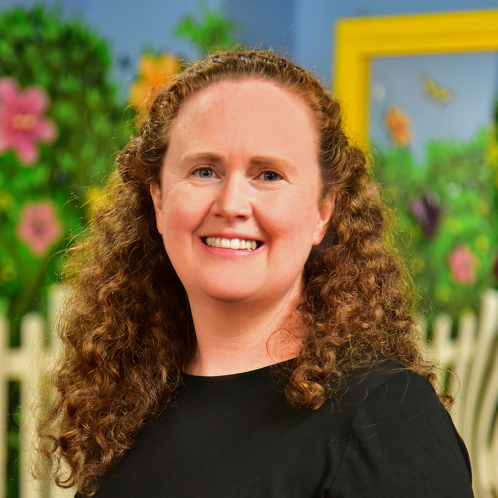 Woman with curly light brown hair wearing black shirt and smiling