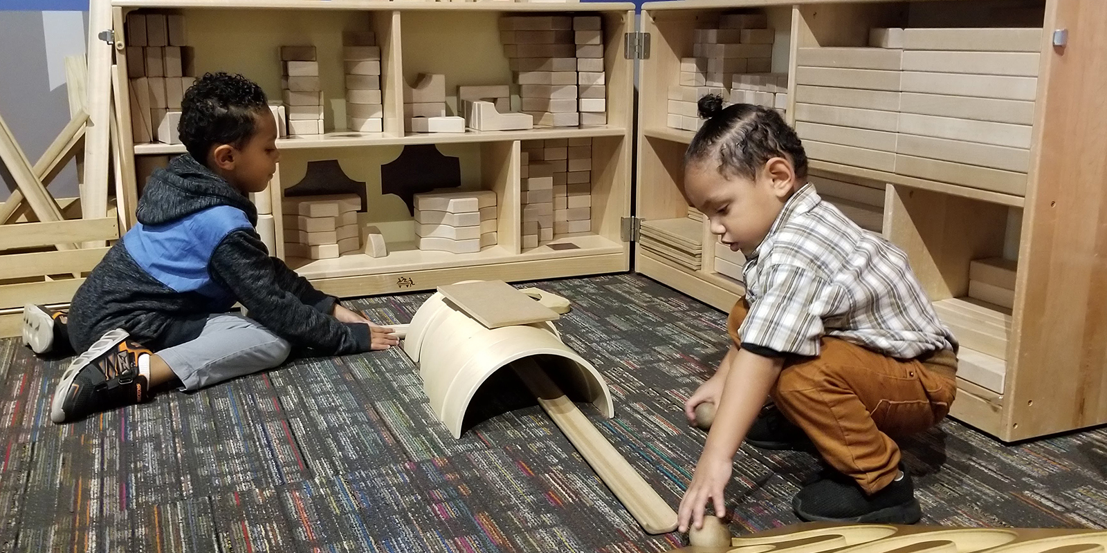 Two young boys playing with wooden block pieces