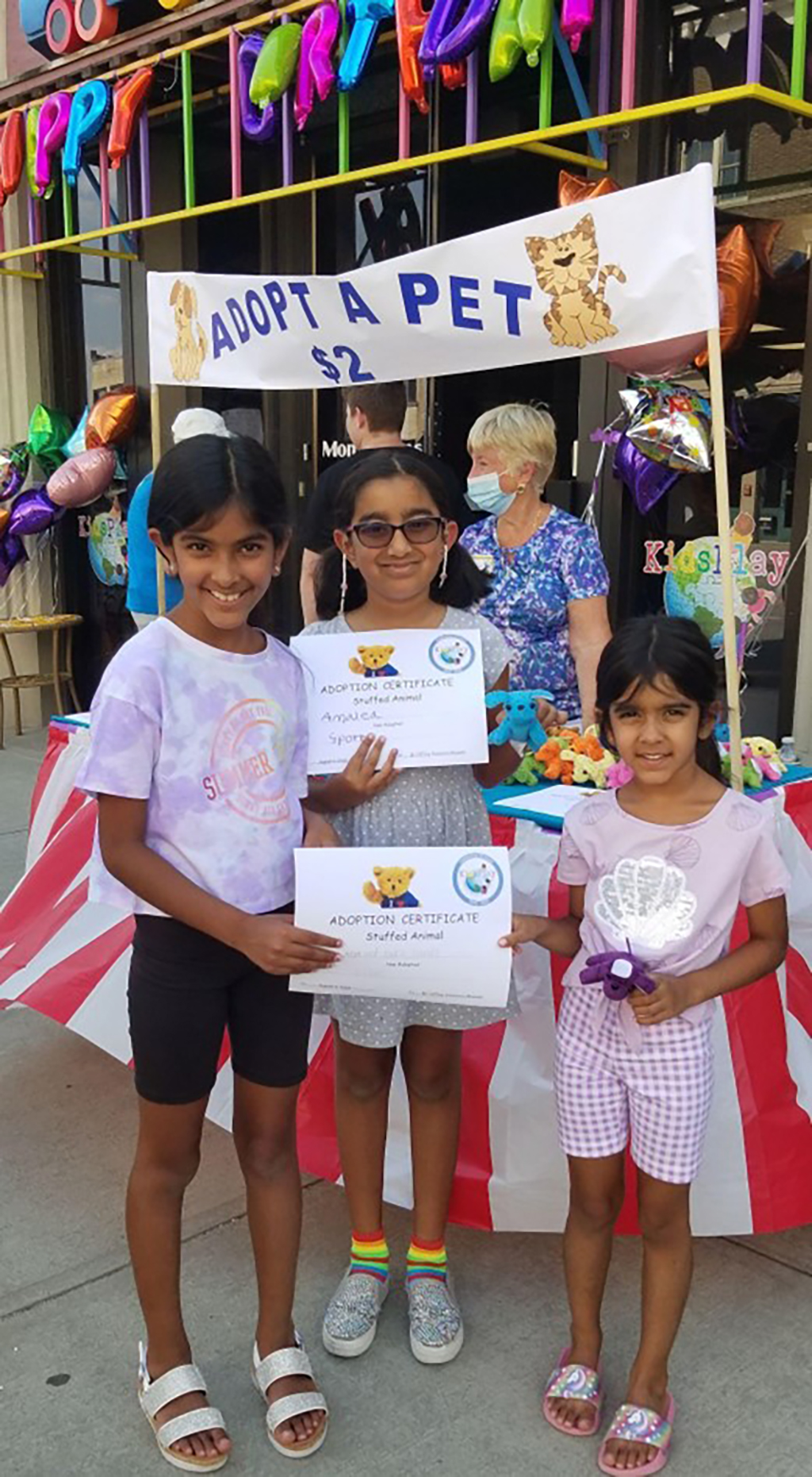KidsPlay Birthday - 4 little girls in front of an Adopt a Pet booth holding Adoption Certificates for stuffed Animals.