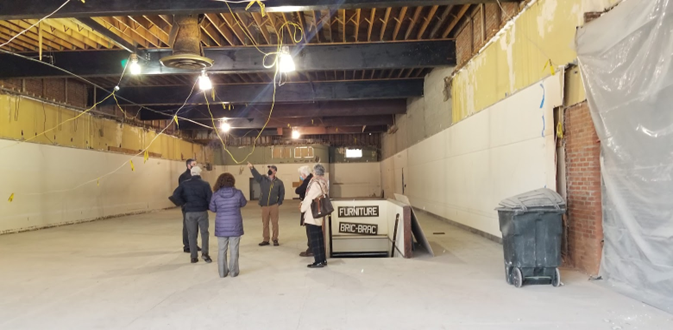An inside look at an unfinished building with people standing in the middle and one pointing to the work that needs to get done.
