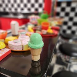 A photo of a plastic toy ice cream cone sitting on the counter of KidsPlay's Diner exhibit.