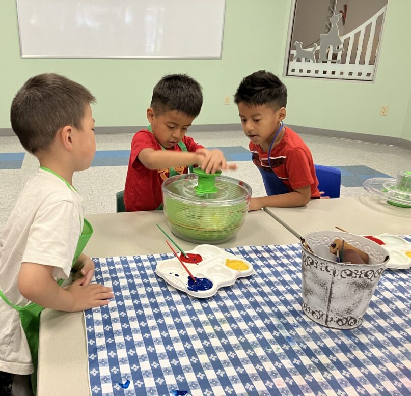 A photo of three boys playing together with paints in KidsPlay's North Gallery Program Room.