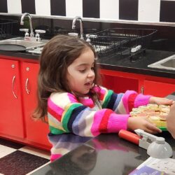 A photo of a little girl in a striped sweater playing in the Diner exhibit at KidsPlay Children's Museum in Torrington, CT. This is for the article "What is the ACM Reciprocal Network?"